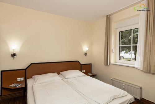 a bed in a bedroom with a window at Boddenhof Apartment 44 - Terrasse, Hund willkommen in Buschvitz