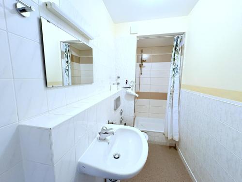 a white bathroom with a sink and a mirror at Boddenhof Apartment 44 - Terrasse, Hund willkommen in Buschvitz