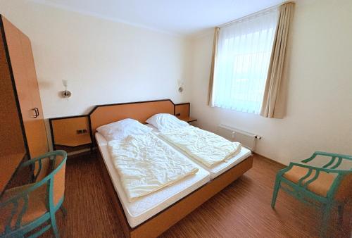 a small bedroom with a bed and two chairs at Boddenhof Apartment 46 - ebenerdig, tierfreundlich in Buschvitz
