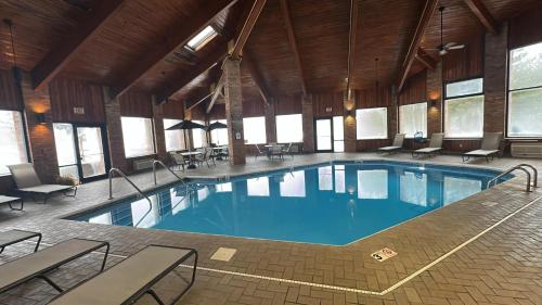 a large swimming pool in a building with tables and chairs at SureStay by Best Western Grove City in Grove City