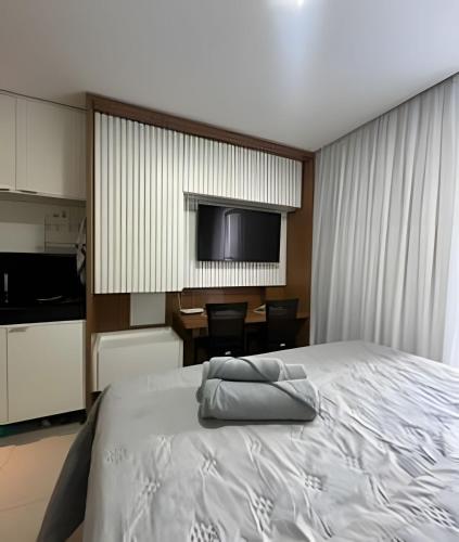 a bedroom with a bed and a table and a television at Flat a 20 metros da praia in João Pessoa