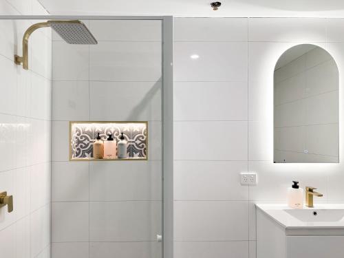 a bathroom with a shower with a sink and a mirror at The Fenway Hostel in Launceston