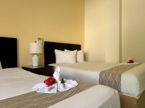 two beds in a hotel room with flowers on them at Nuevo Paris Hotel in Mérida