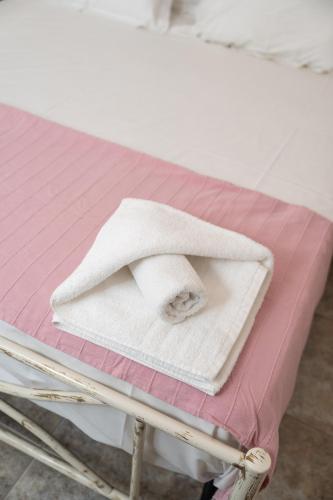a white towel sitting on top of a bed at Azure Garden Retreat in Aigio