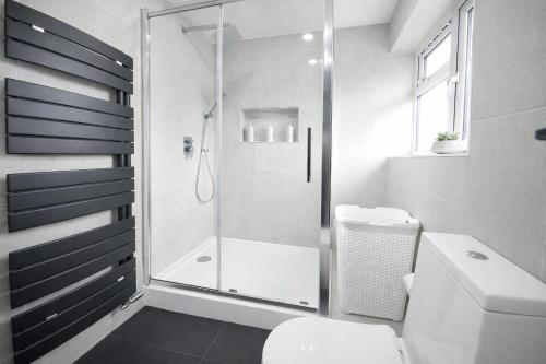 a white bathroom with a shower and a toilet at Spacious 5BR Home with Garden, Games & Parking Near Heathrow Windsor in Slough