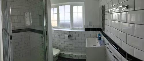 a white tiled bathroom with a sink and a mirror at Groombridge 1 Bed self catered flat, can sleep 2 in Groombridge