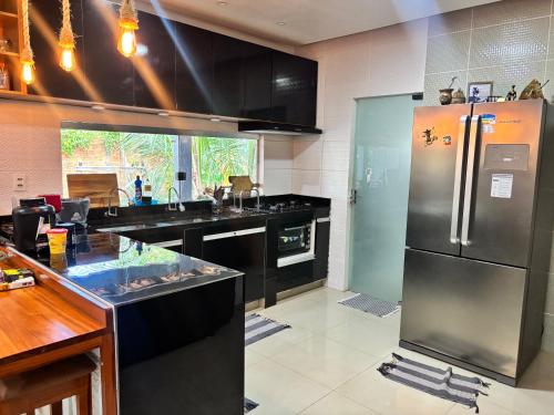a kitchen with a stainless steel refrigerator and black counters at Casa chácara para alugar no período do festival de Parintins in Parintins