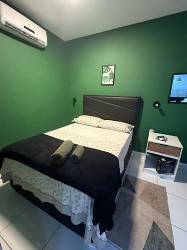 a bedroom with a bed and a green wall at Loft Dominguinhos in Campina Grande
