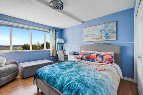 a blue bedroom with a bed and a couch at Stunning oceanfront home 4br3b sunrise beachcombing near Bamberton Park in Mill Bay