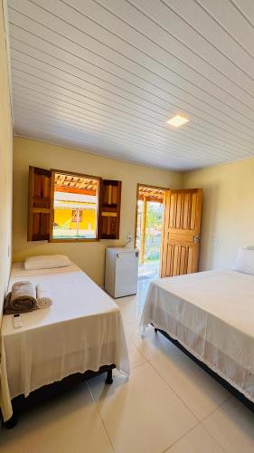a bedroom with two beds and a window at Hospedaria Hibisco Xandó - Caraíva in Caraíva