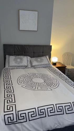 a bed with a black and white comforter on it at PLUS Properties Moston in Stoke on Trent