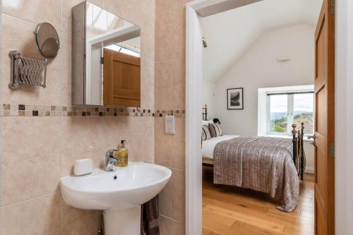 a bathroom with a sink and a bedroom with a bed at 3 Bed in Corwen oc-fl009 in Derwen