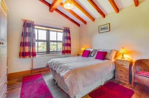 a bedroom with a bed with pink pillows and a window at 3 Bed in Caernarfon oc-wag443 in Llanwnda