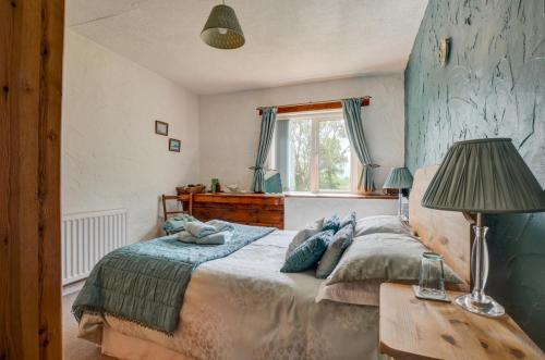 a bedroom with a bed and a table with a lamp at 3 Bed in Llanfairpwllgwyngyll oc-wai194 in Dwyran