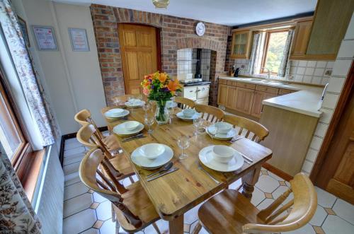 a kitchen with a wooden table with chairs and flowers at 3 Bed in Fishguard oc-wav276 in Pontfaen