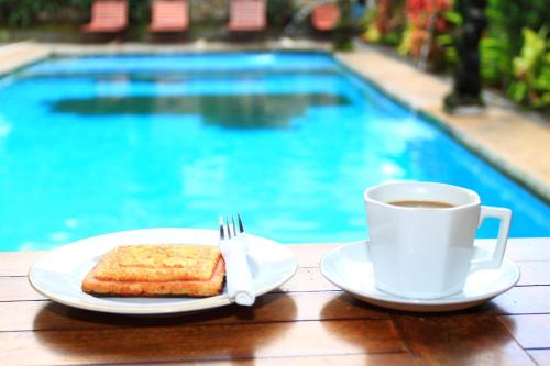 Ein Teller Toast und eine Tasse Kaffee neben einem Pool in der Unterkunft Warsa's Garden Bungalow and Spa in Ubud