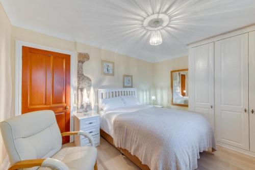 a white bedroom with a bed and a chair at 3 Bed in Benllech oc-24195 in Benllech