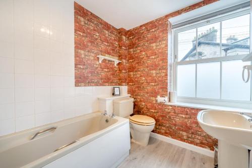a bathroom with a white tub and a brick wall at 2 Bed in Kendal oc-gl097 in Kendal