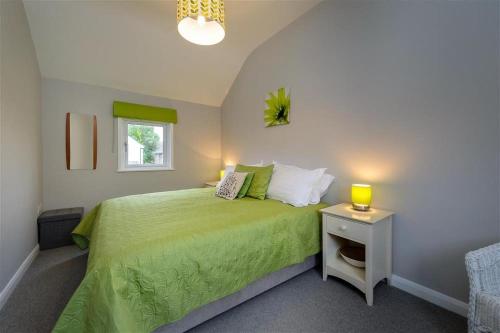 a bedroom with a green bed with a night stand at 4 Bed in Pwllheli oc-lluest in Abersoch