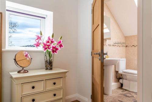 a bathroom with a vase of flowers on a dresser with a mirror at 1 Bed in Corwen oc-fl010 in Derwen