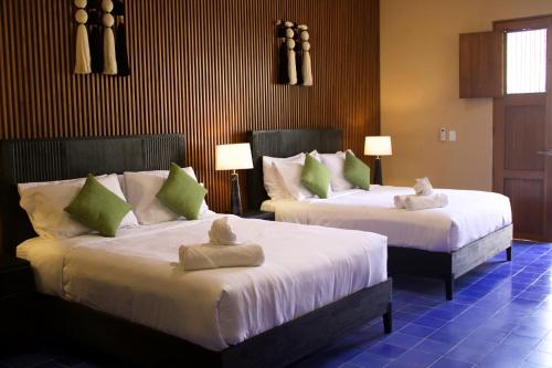 ein Hotelzimmer mit zwei Betten, auf denen Handtücher liegen in der Unterkunft Casa Ku'x in Mérida