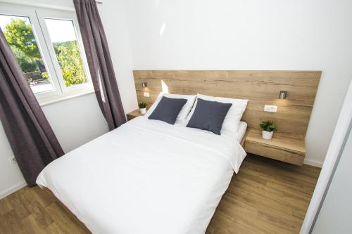 een slaapkamer met een groot wit bed en een raam bij Olive Tree Apartments in Vodice
