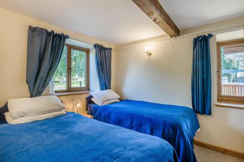two beds in a room with blue curtains at 2 Bed in Smallburgh oc-h33733 in Dilham