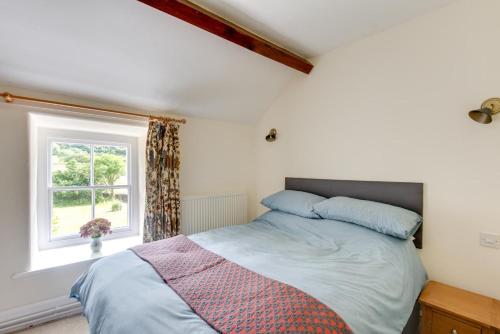 a bedroom with a bed and a window at 3 Bed in Tywyn oc-bow248 in Abergynolwyn