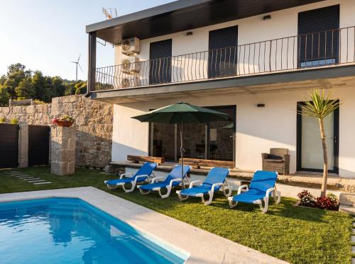 a group of chairs and an umbrella next to a swimming pool at Casa do Abade - Country House in Viseu