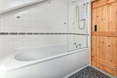 a white bath tub in a white tiled bathroom at 2 Bed in Nefyn oc-tynixs in Nefyn