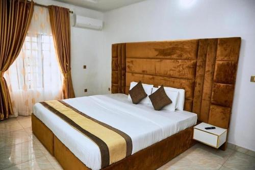 a bedroom with a large bed with a wooden headboard at Executive Luxury Room - Sleeps 2 - Pool - Gym in Lagos