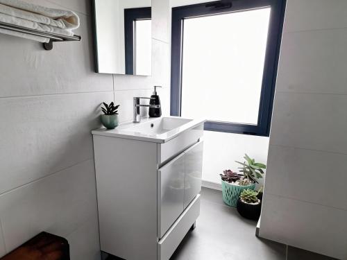 a white kitchen with a sink and a window at Casa do Abade - Country House in Viseu
