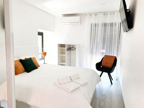 a white bedroom with a large white bed and a chair at Casa do Abade - Country House in Viseu