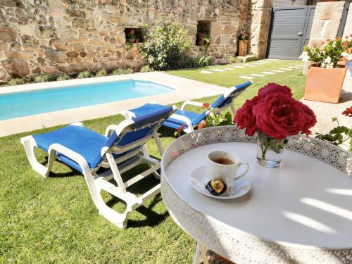 a table with a cup of coffee and chairs next to a pool at Casa do Abade - Country House in Viseu