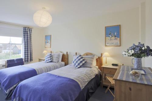 a bedroom with two beds and a desk and a table at 3 Bed in Walberswick oc-aaferr in Walberswick