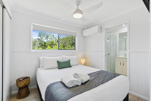 a white bedroom with a bed with towels on it at Ingenia Holidays Kinka Beach Yeppoon in Kinka