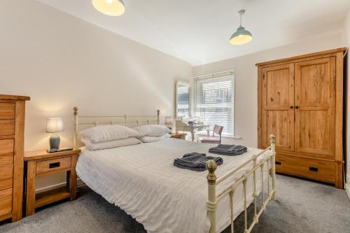 a bedroom with a white bed and a wooden cabinet at 3 Bed in Swanage oc-wy272 in Swanage