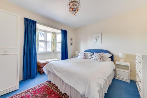 a bedroom with a large bed with blue curtains at 4 Bed in Southwold oc-spn in Reydon