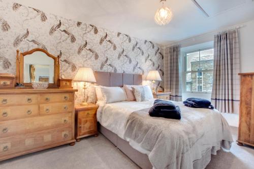 a bedroom with a bed with a dresser and a mirror at 3 Bed in Hawes oc-ds1009 in Hawes