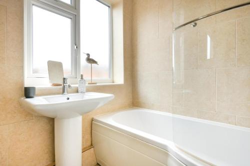 a white bathroom with a sink and a bath tub at 3 Bed in Pwllheli oc-hillvi in Llanbedrog