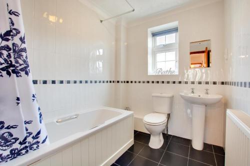 a bathroom with a tub and a toilet and a sink at 2 Bed in Sheringham oc-2029 in Sheringham