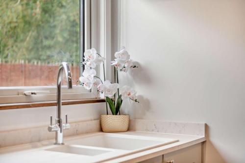 a kitchen sink with a vase of flowers in a window at 3 Bed in Acton oc-c28929 in Waldingfield