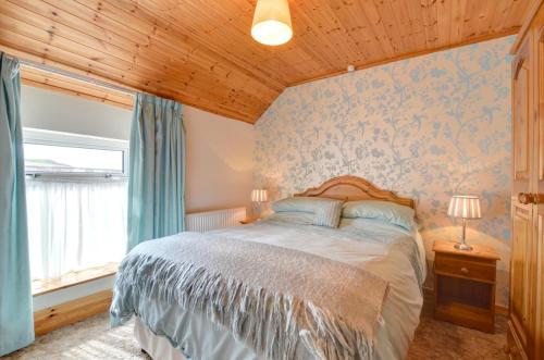 a bedroom with a large bed with blue wallpaper at 3 Bed in Pwllheli oc-wag486 in Bryncroes