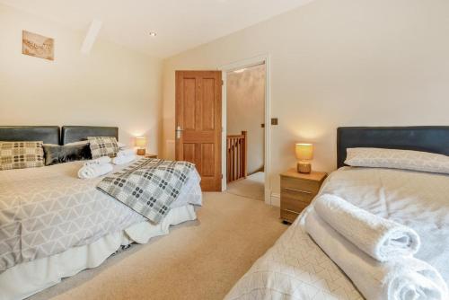 two beds in a bedroom with two lamps and a door at 2 Bed in Llandysul oc-was280 in Rhyd Lewis
