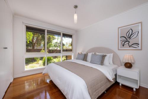 a white bedroom with a bed and a window at Sundance steps to Half Moon Bay in Black Rock North