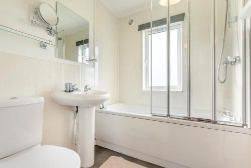 a white bathroom with a tub and a sink and a toilet at 3 Bed in St. Merryn oc-k30138 in Saint Merryn