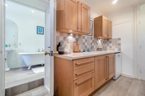 a kitchen with wooden cabinets and a sink and a tub at 2 Bed in Felixstowe oc-m30281 in Felixstowe