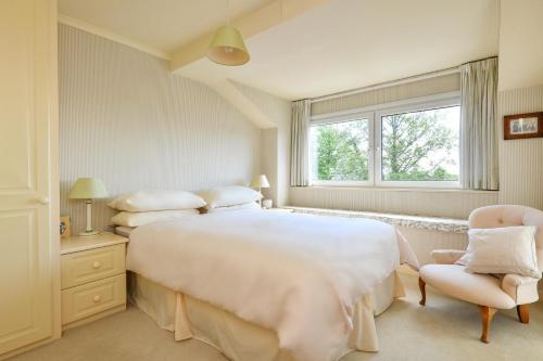 a white bedroom with a large bed and a chair at 3 Bed in Llanbedrog oc-gerddi in Llanbedrog