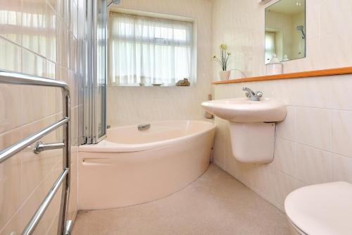 a bathroom with a sink and a tub and a toilet at 3 Bed in Llanbedrog oc-gerddi in Llanbedrog