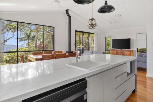 eine Küche mit weißer Arbeitsplatte und ein Wohnzimmer in der Unterkunft Edges by St Bernards Hotel in Mount Tamborine